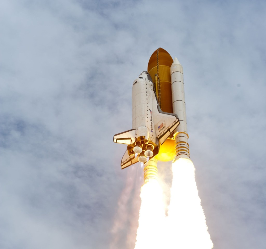 white and gold rocket launching toward blue sky